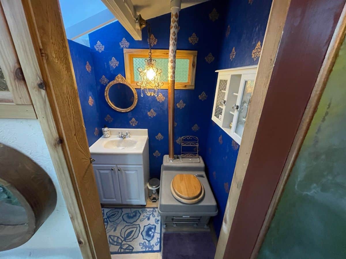 blue wall of bathroom with white cabinet inside door next to toilet