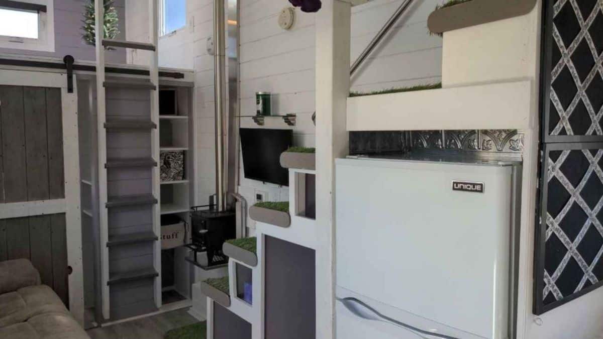 A small closet and wall mounted TV set is installed in living area of 2 Bedroom Tiny House