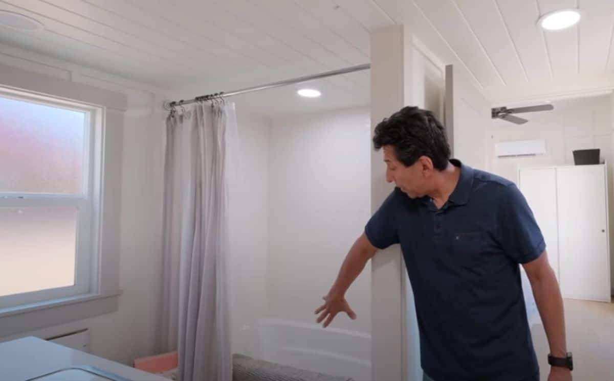 man showing bathtub and shower combination in tiny home