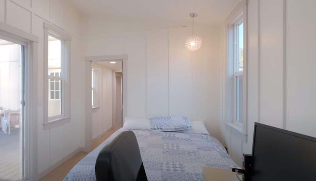 open door to bedroom on left with bed against wall on right