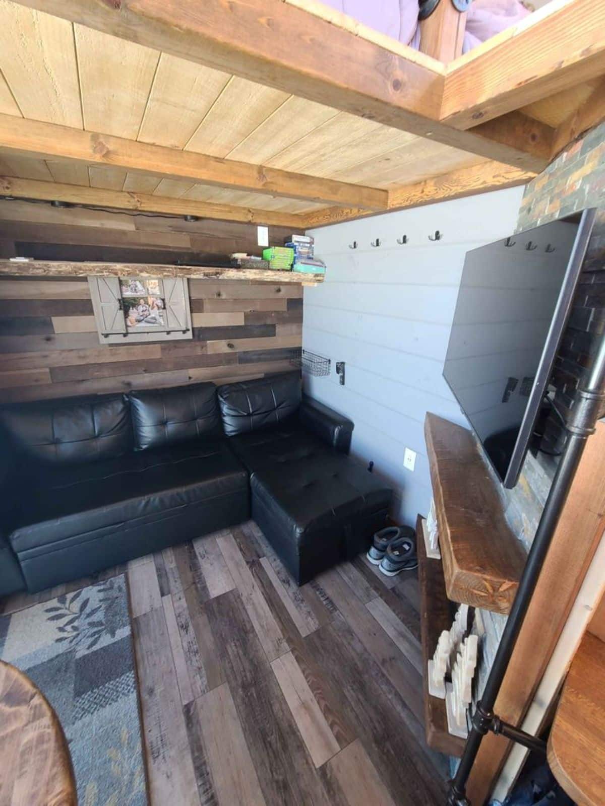 Living area of 21' Display Model Tiny Home has L shaped couch and wall mounted TV set