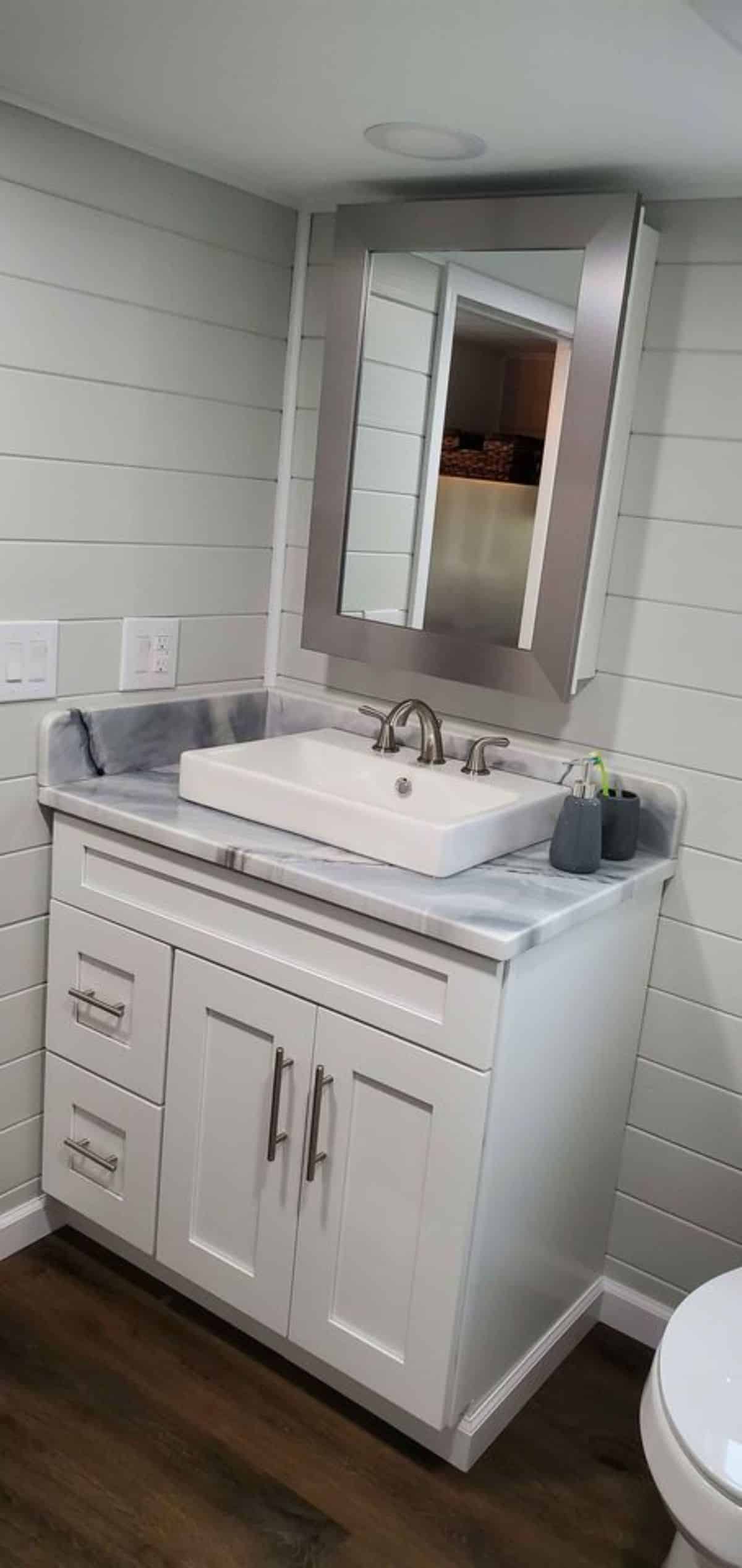 Sink with vanity and mirror in bathroom of 24' Brand New Tiny Home