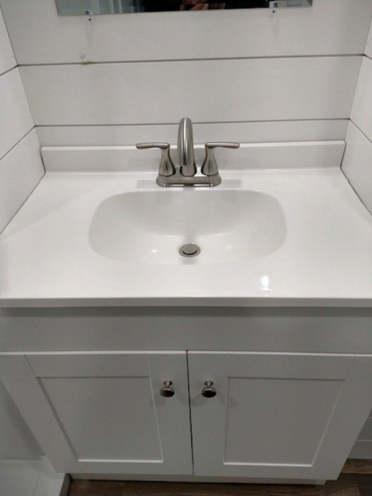 Sink with vanity and mirror in bathroom of brand new tiny house
