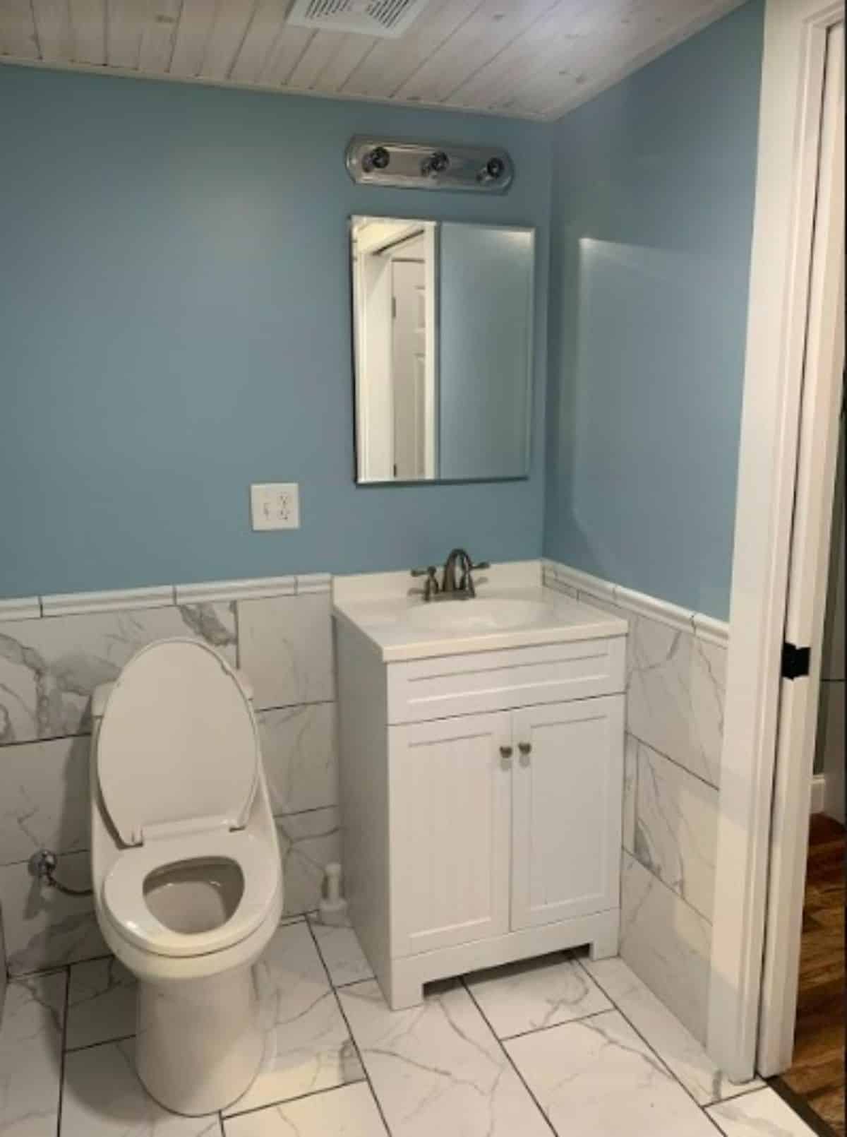 Standard toilet, sink with vanity & mirror in stunning bathroom of Airbnb Tiny Home