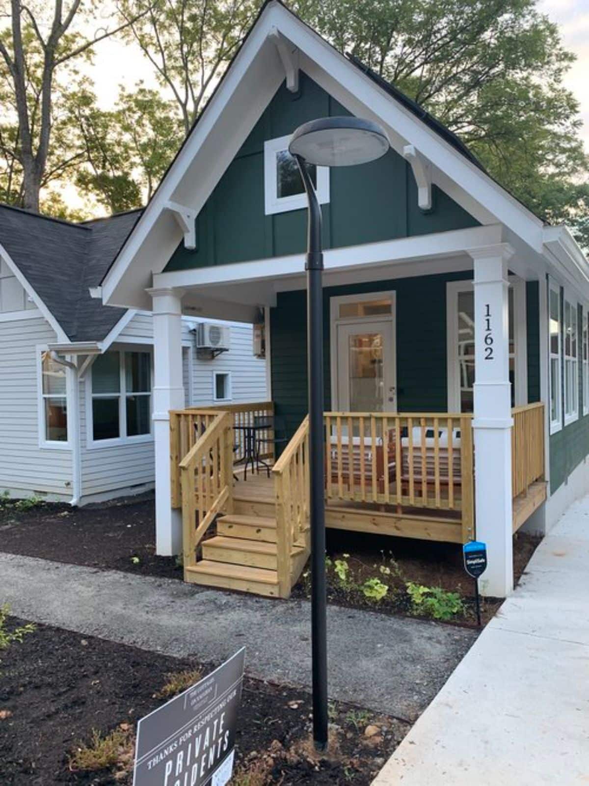 wood porch on front of gray and white tiny home