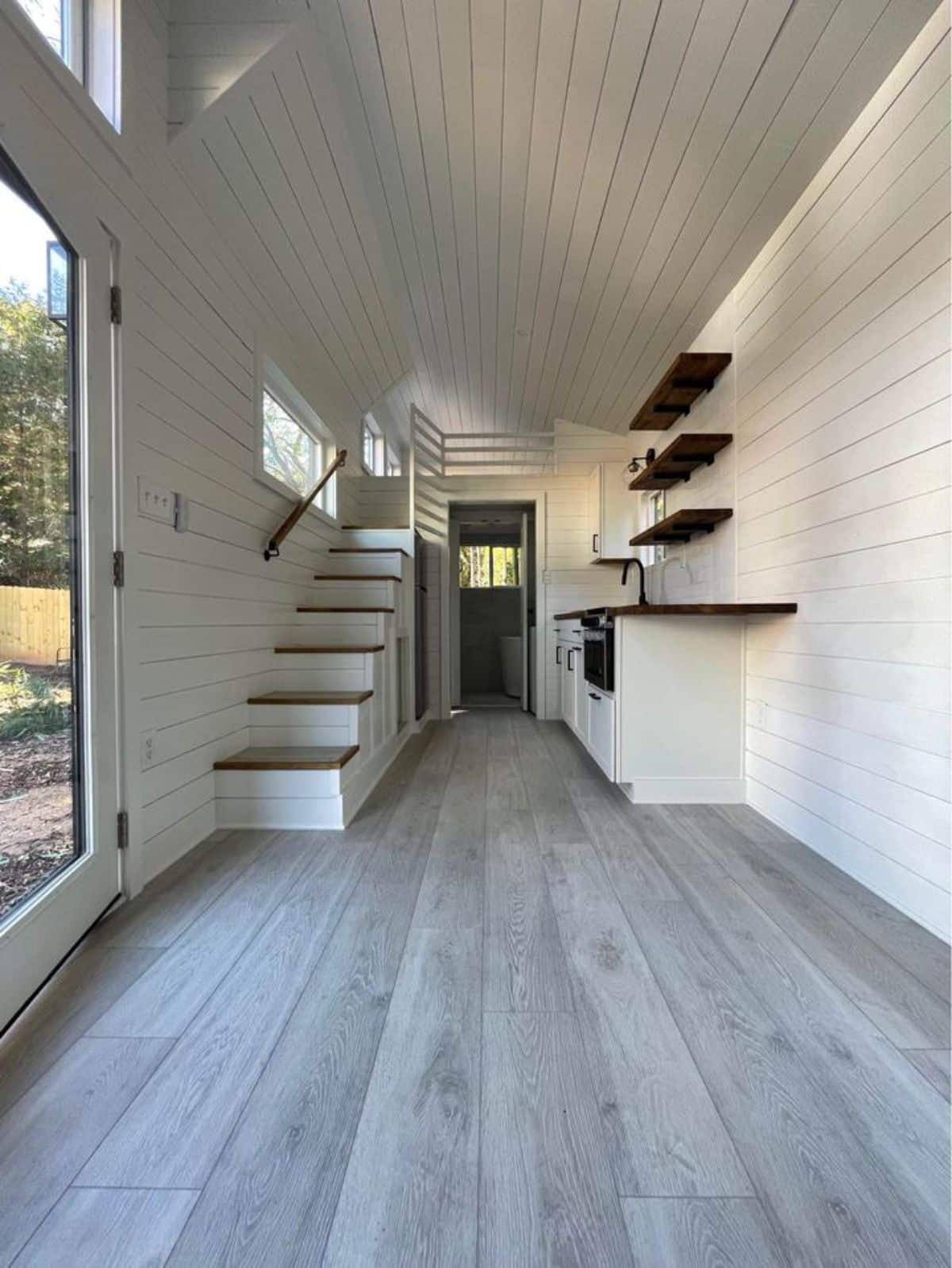 Overall interiors with hardwood flooring and shiplap walls of Certified Tiny House on Wheels from living room view