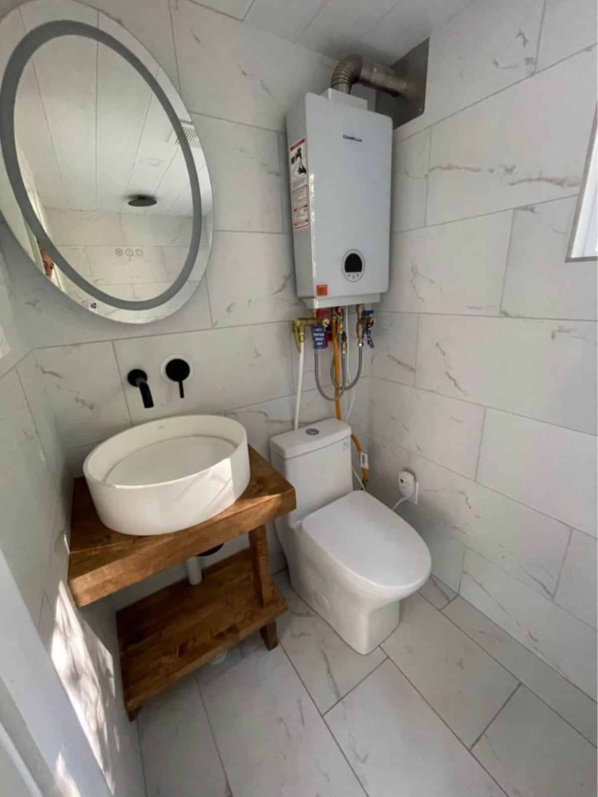 Amazing Sink with mirror and standard toilet is installed in bathroom of Certified Tiny House on Wheels