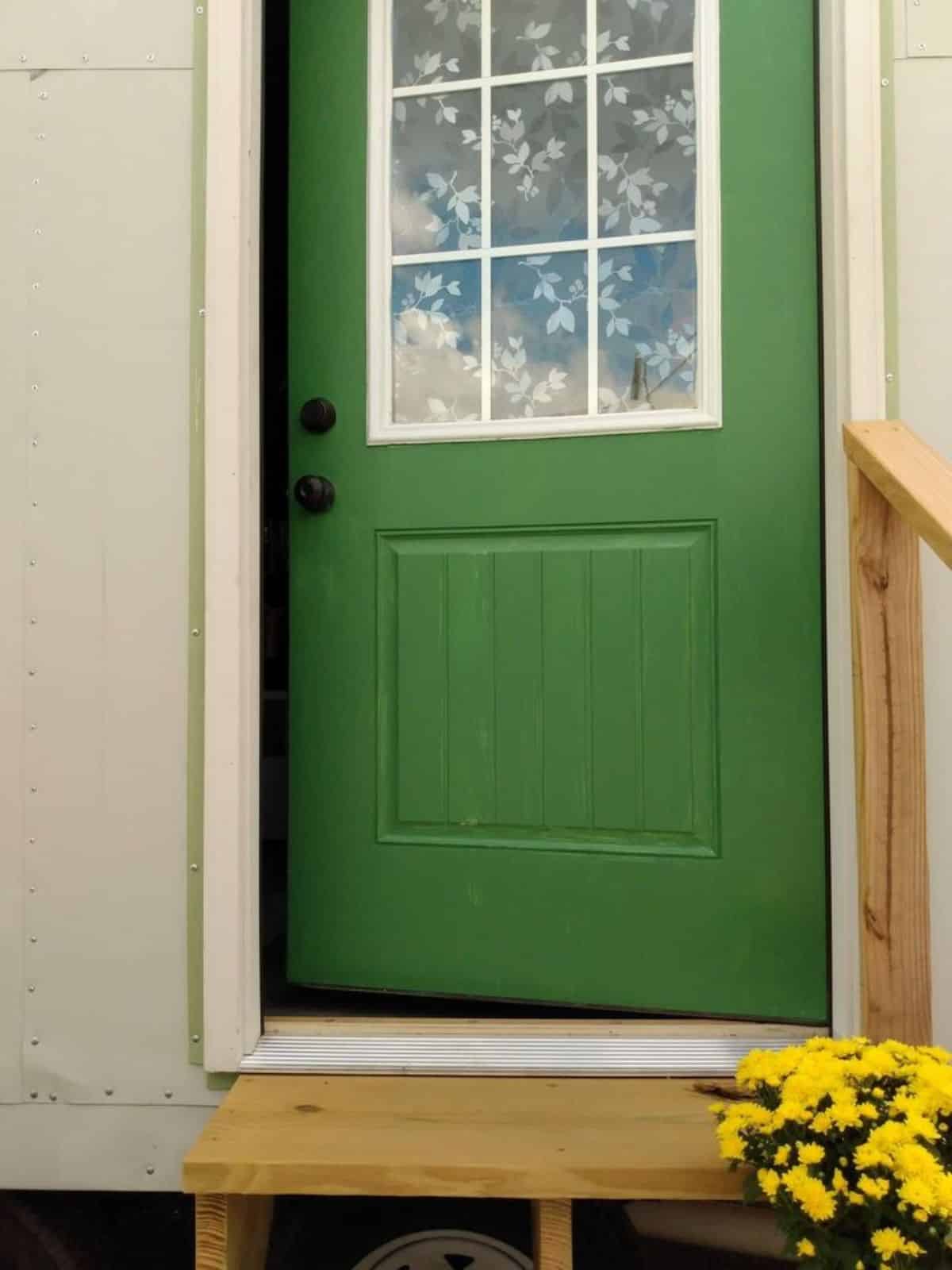 Green colored main door of charming tiny home