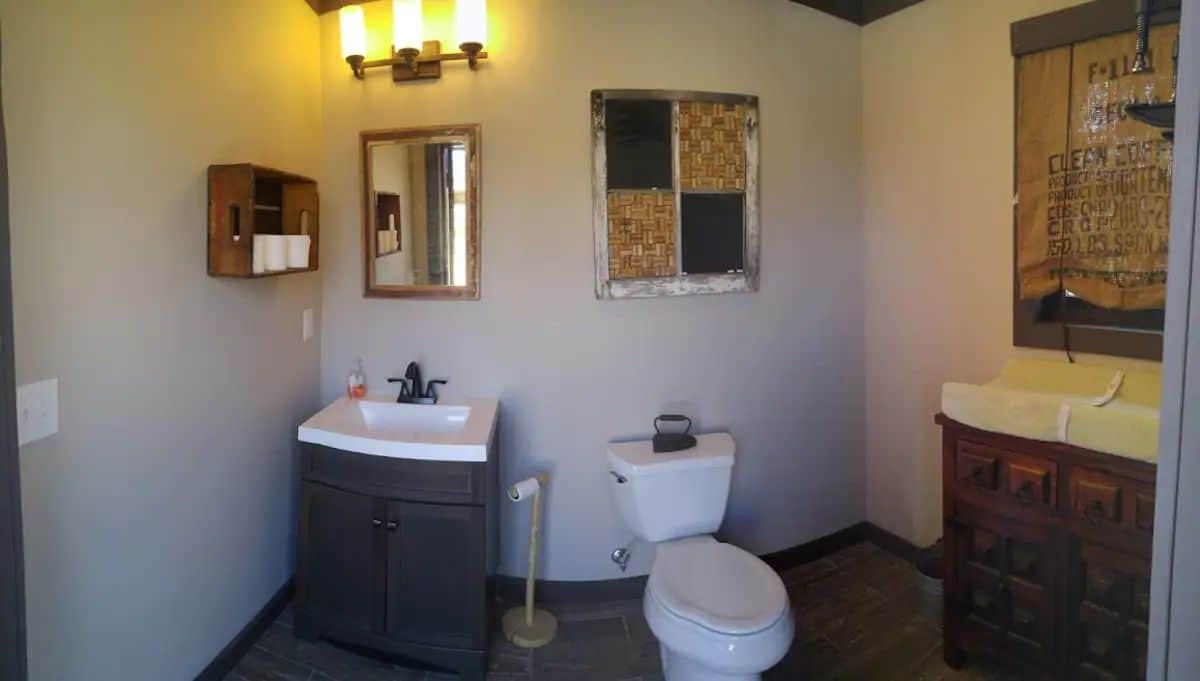 white toilet next to dark cabinet with white counters and changing table on right