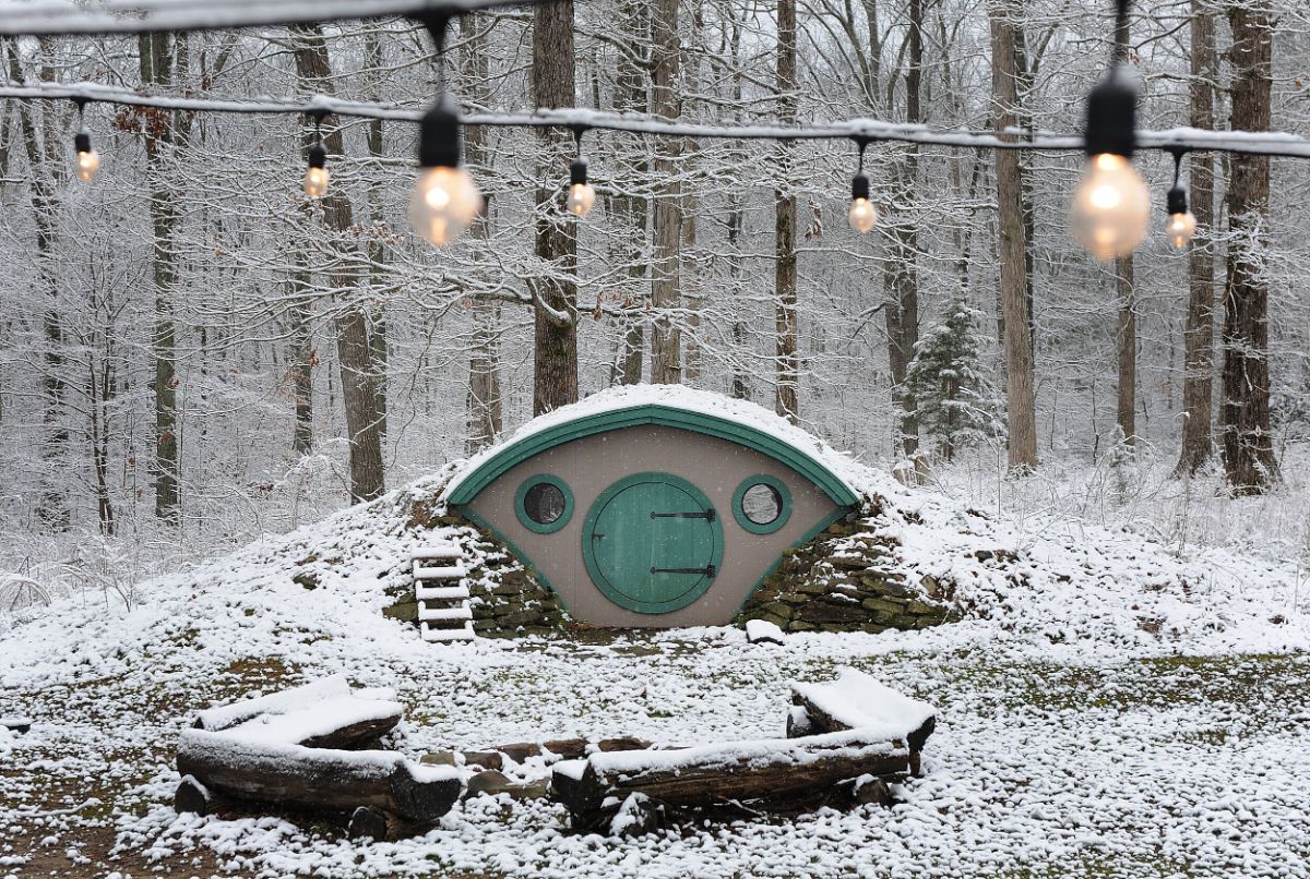 snow on wooden bench in front of hobbit hut