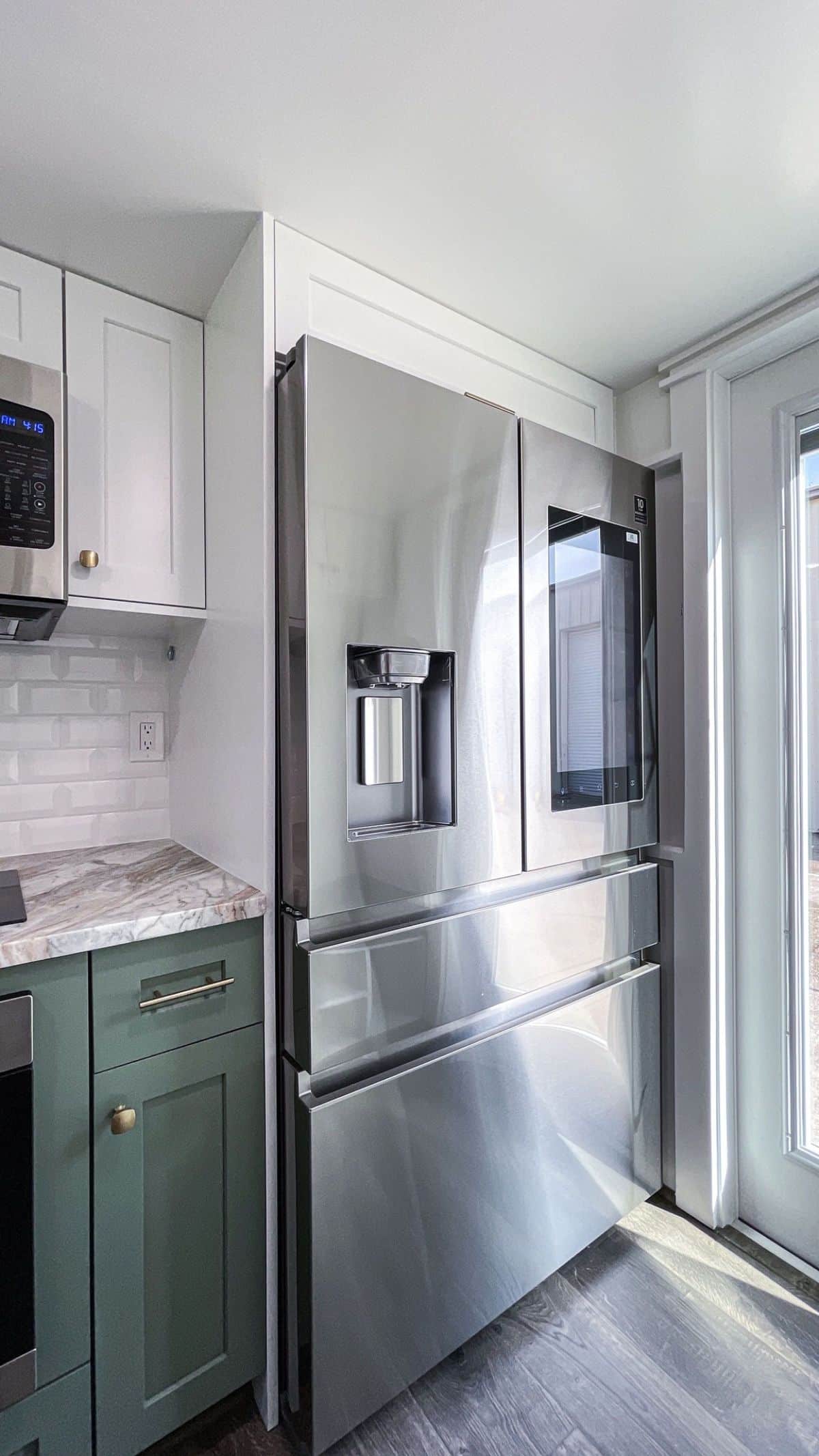 stainless steel refrigerator next to green cabinet