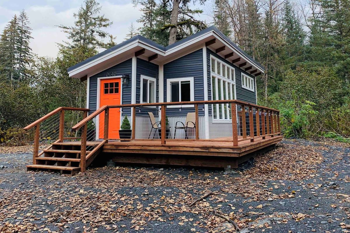 blue siding and orange door on tiny house with porch