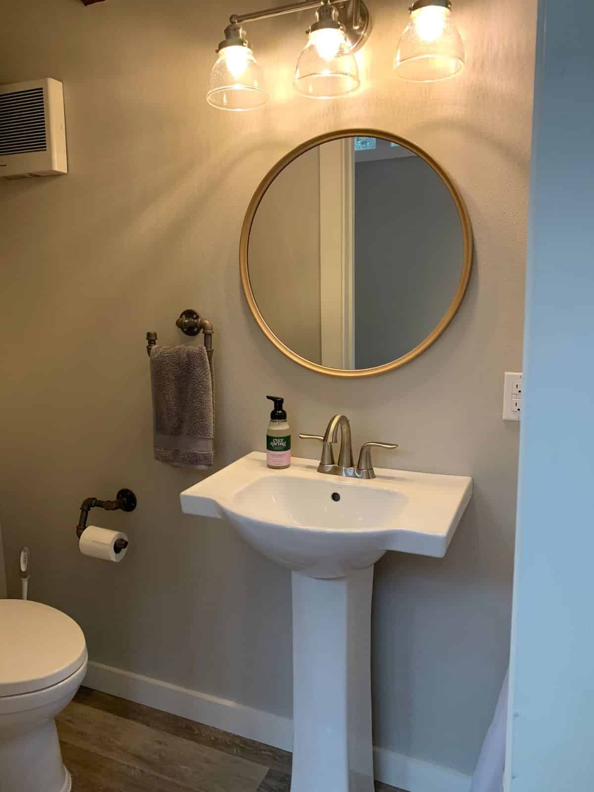 white pedestal sink under round mirror
