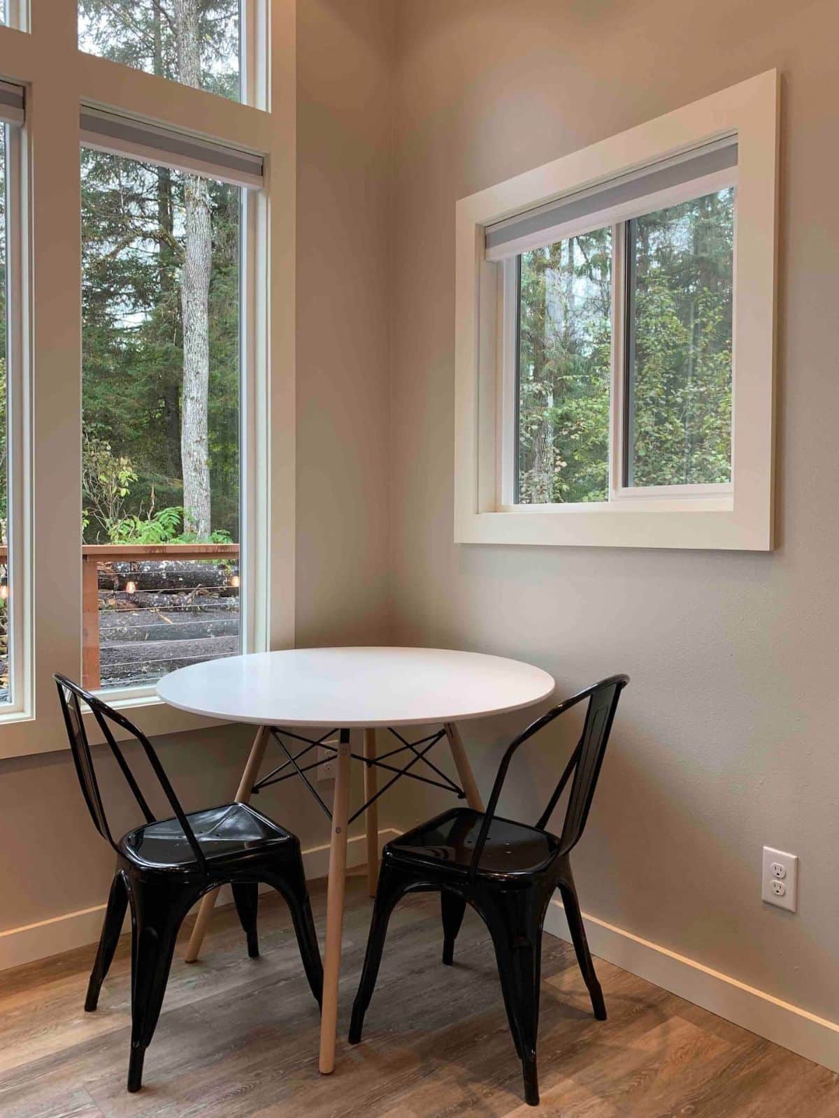 round table with black chairs in corner by windows