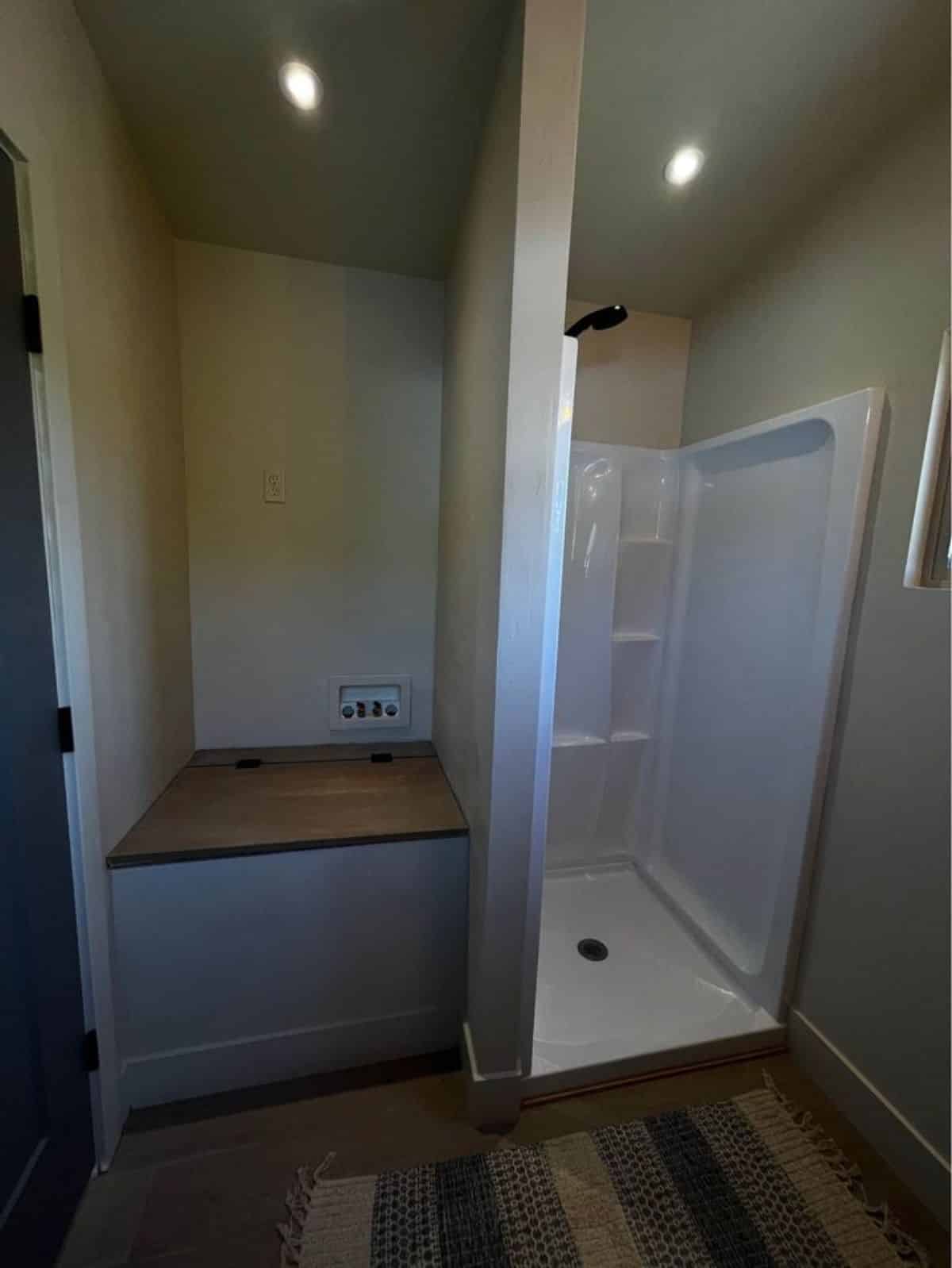 Bathroom of newly constructed 30’ tiny home has a separate shower area with space for washer dryer combo