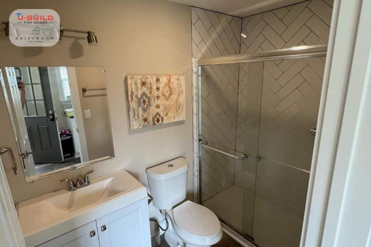 Bathroom has standard toilet, sink with vanity & mirror and separate shower area with glass door