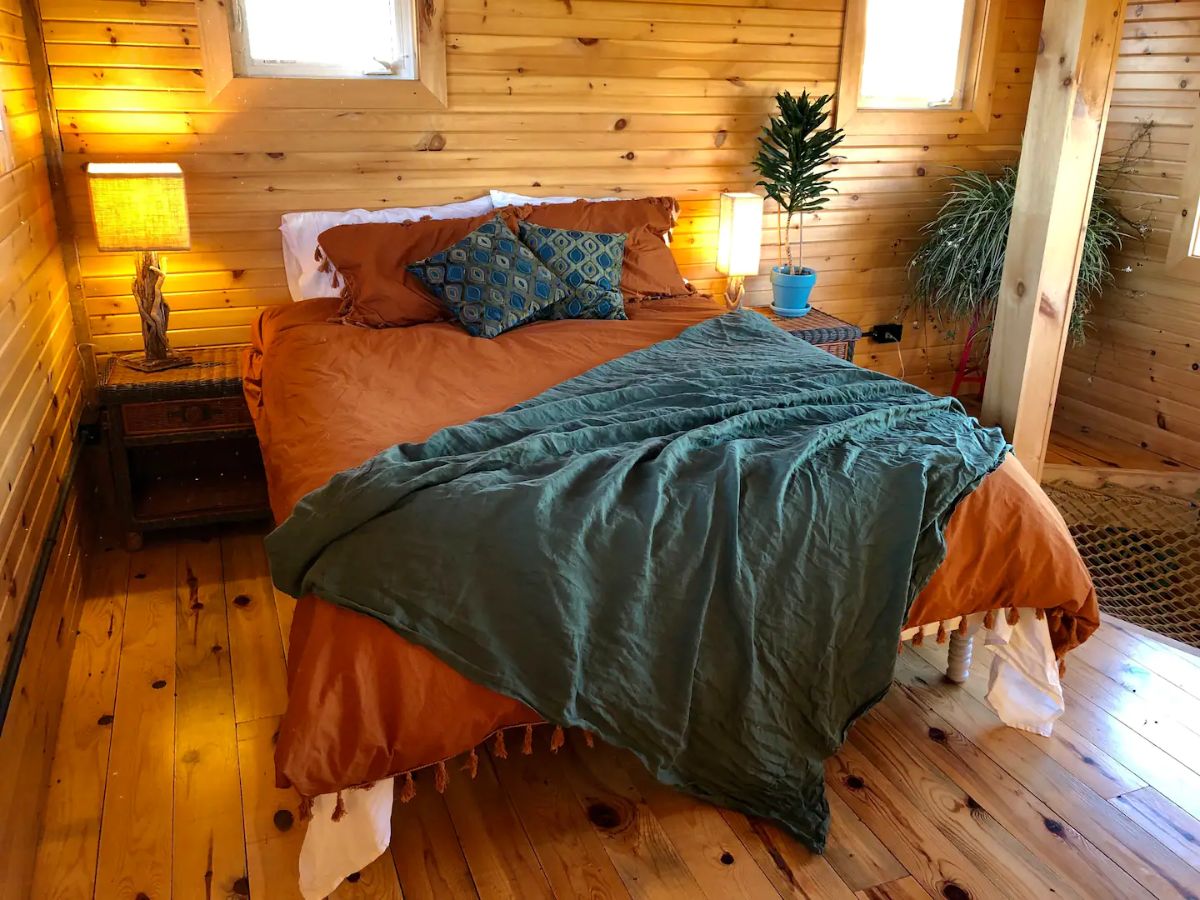 pickalotta tiny home bedroom with orange duvet and green balnket on bed