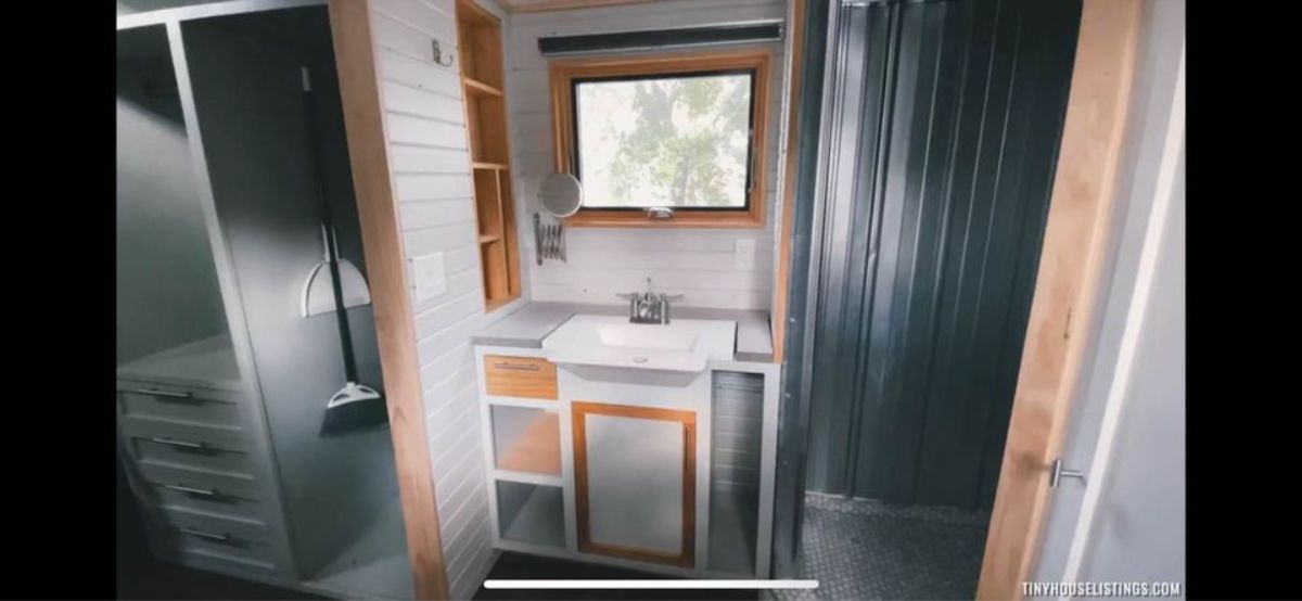 Standard toilet and sink with vanity & mirror in bathroom of Professionally Built 30' Tiny House