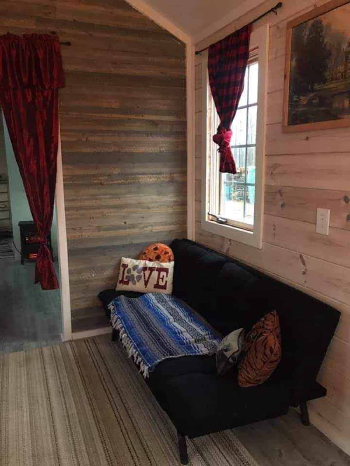 Living area of Rustic tiny home  has a couch and huge window