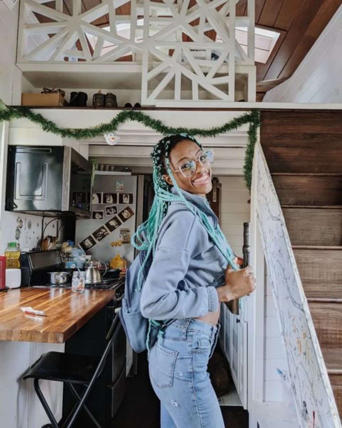 woman in denim with backpack inside tiny house kitchen