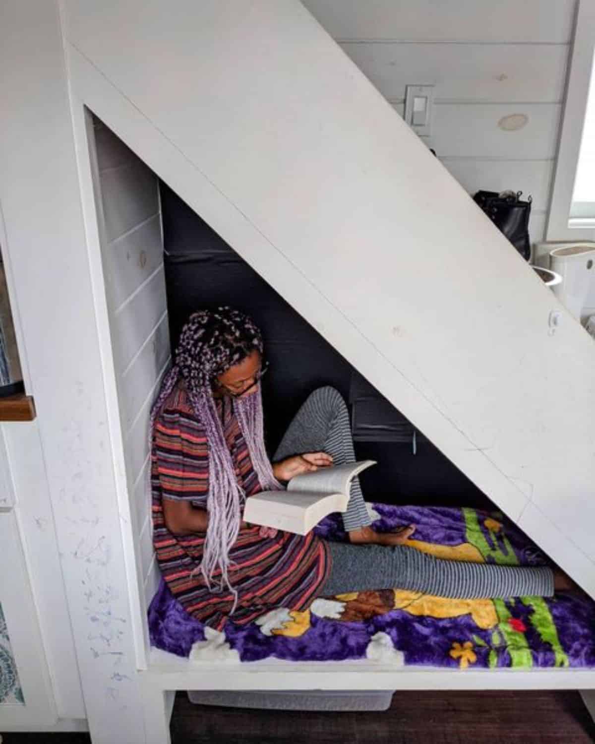 woman under stairs in nook reading