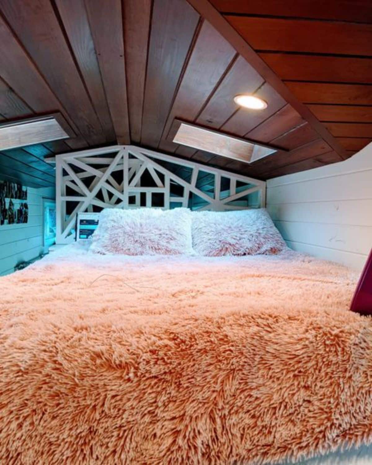 peach fluffy blanket on bed in loft with geometyric wall in background