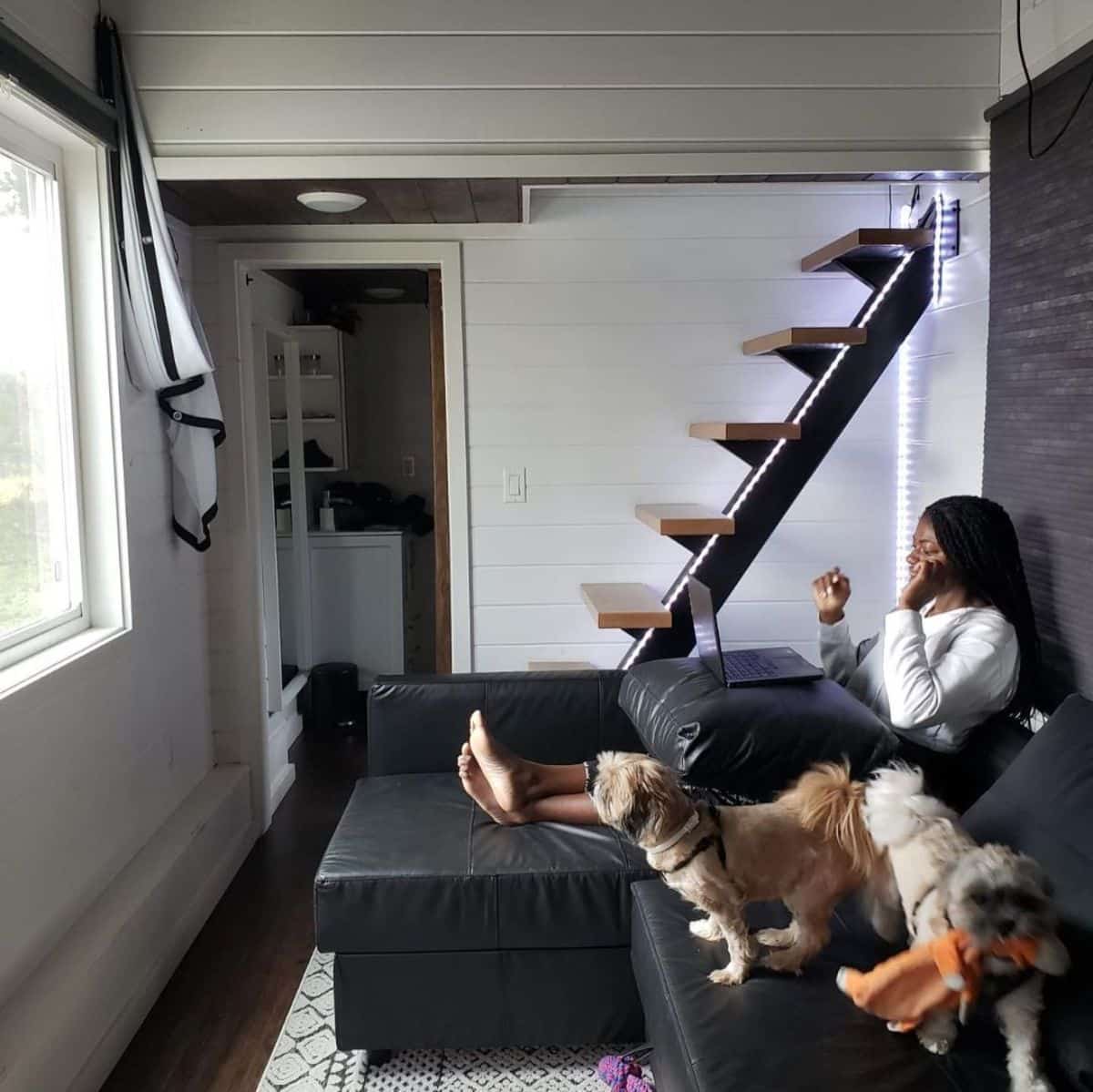 woman and dogs on sofa in front of stairs to loft