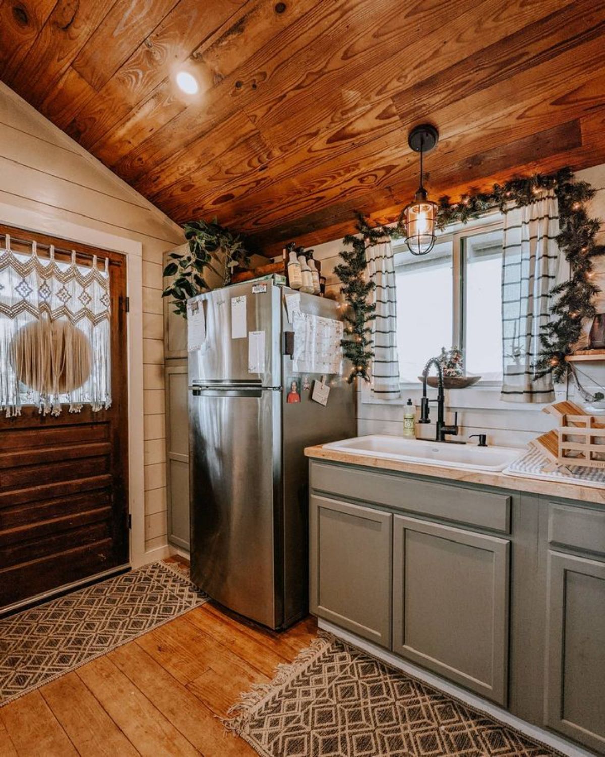 texas tiny farmhouse interior with gray kitchen cabinets on right and wood door in background