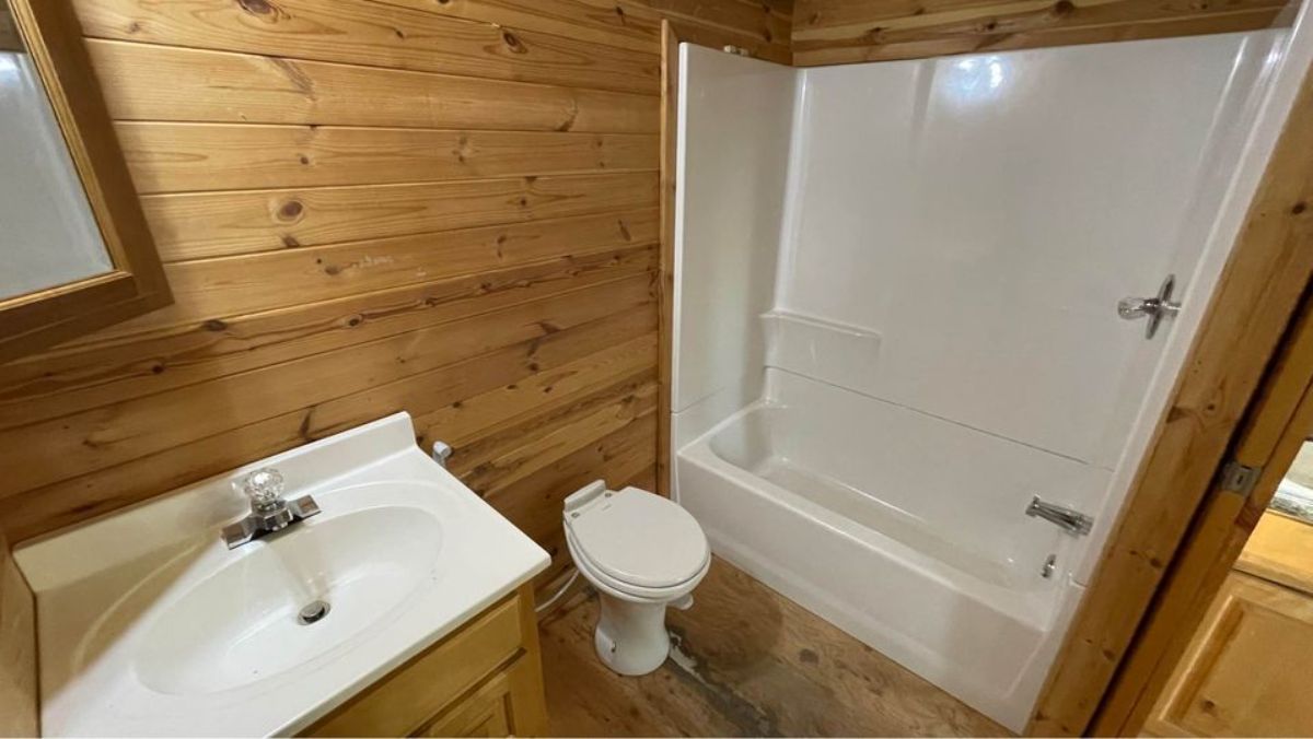 Bathroom of Tiny Towable home has a standard toilet, sink and a shower with tub