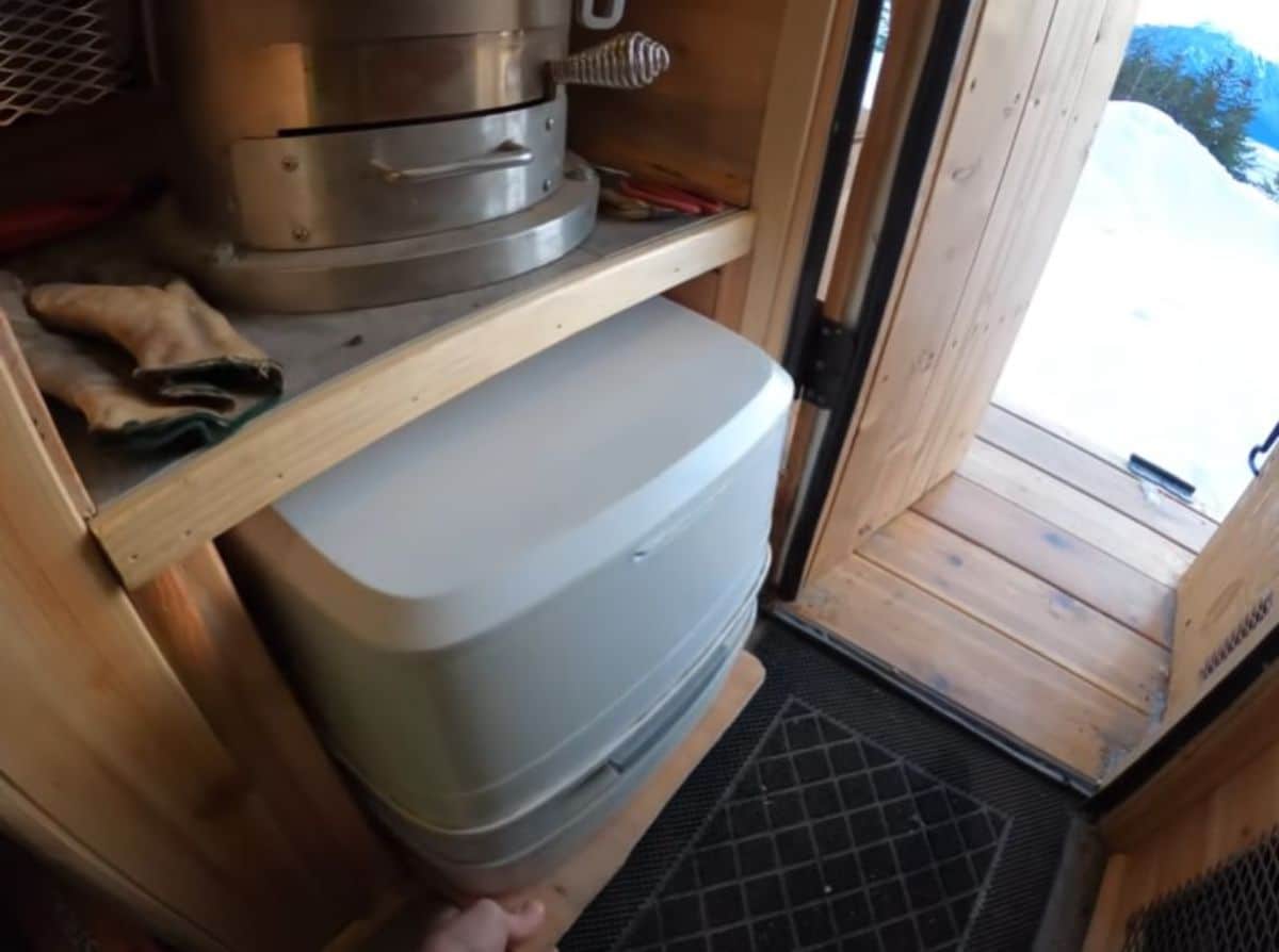 white compost toilet underneath shelf