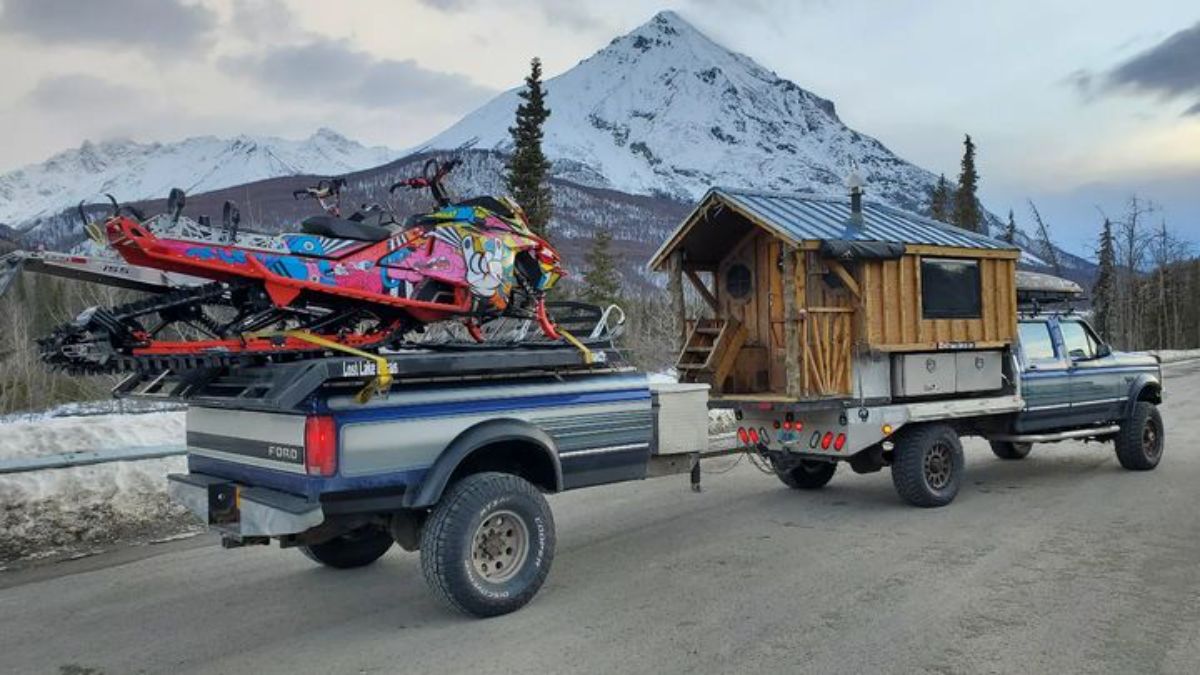 blue truck with wood camper on back hauling truck bed