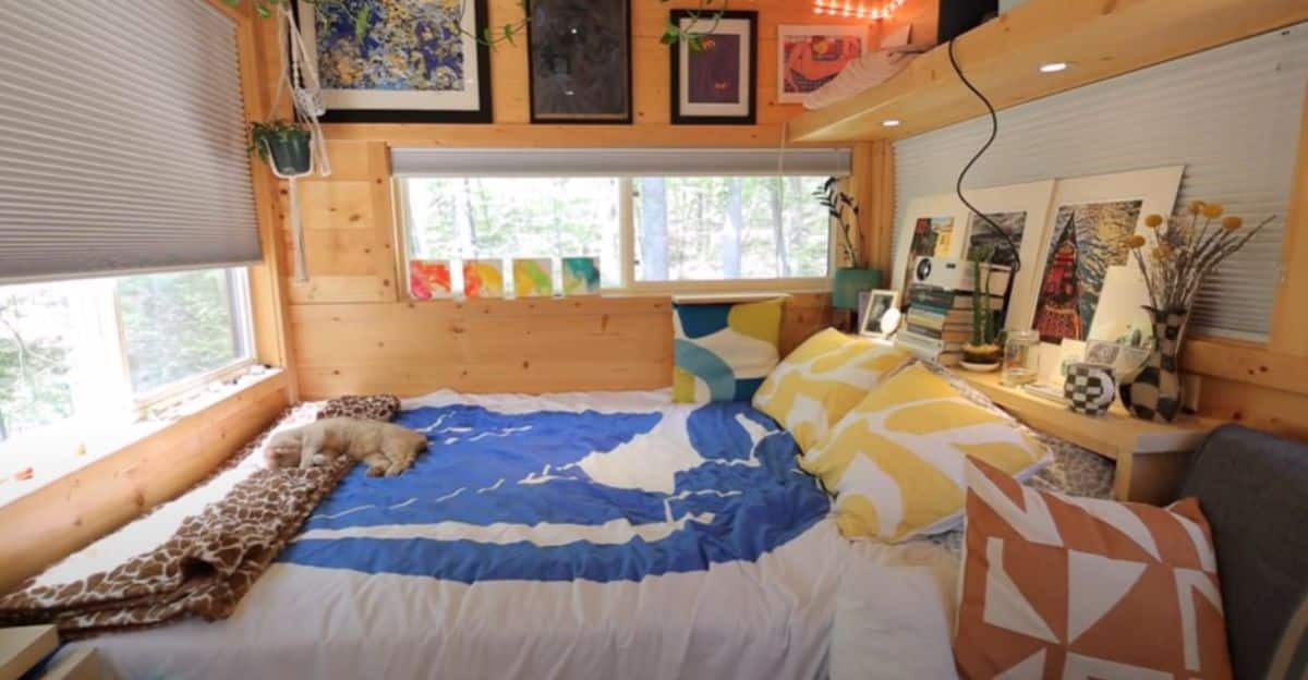 bed against back wall of tiny home with cat on the end