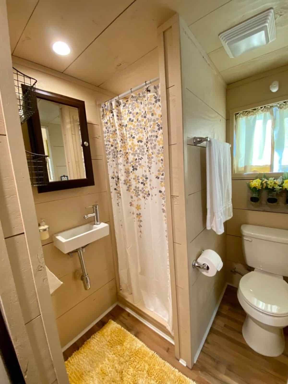 Stylish bathroom has a standard toilet, sink with mirror and separate shower area
