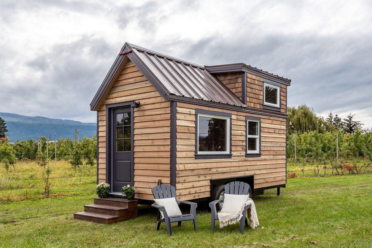 wood siding and gray trim on tiny house in grass lot