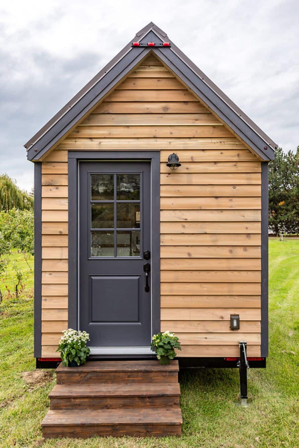 gray door on end of tiny home with wood siding