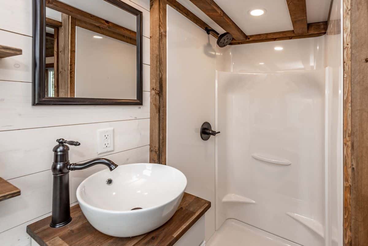 white bowl sink over wood cabinet on vanity in tiny house with white shower stall