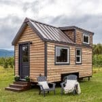 wood siding and gray trim on tiny house in grass lot