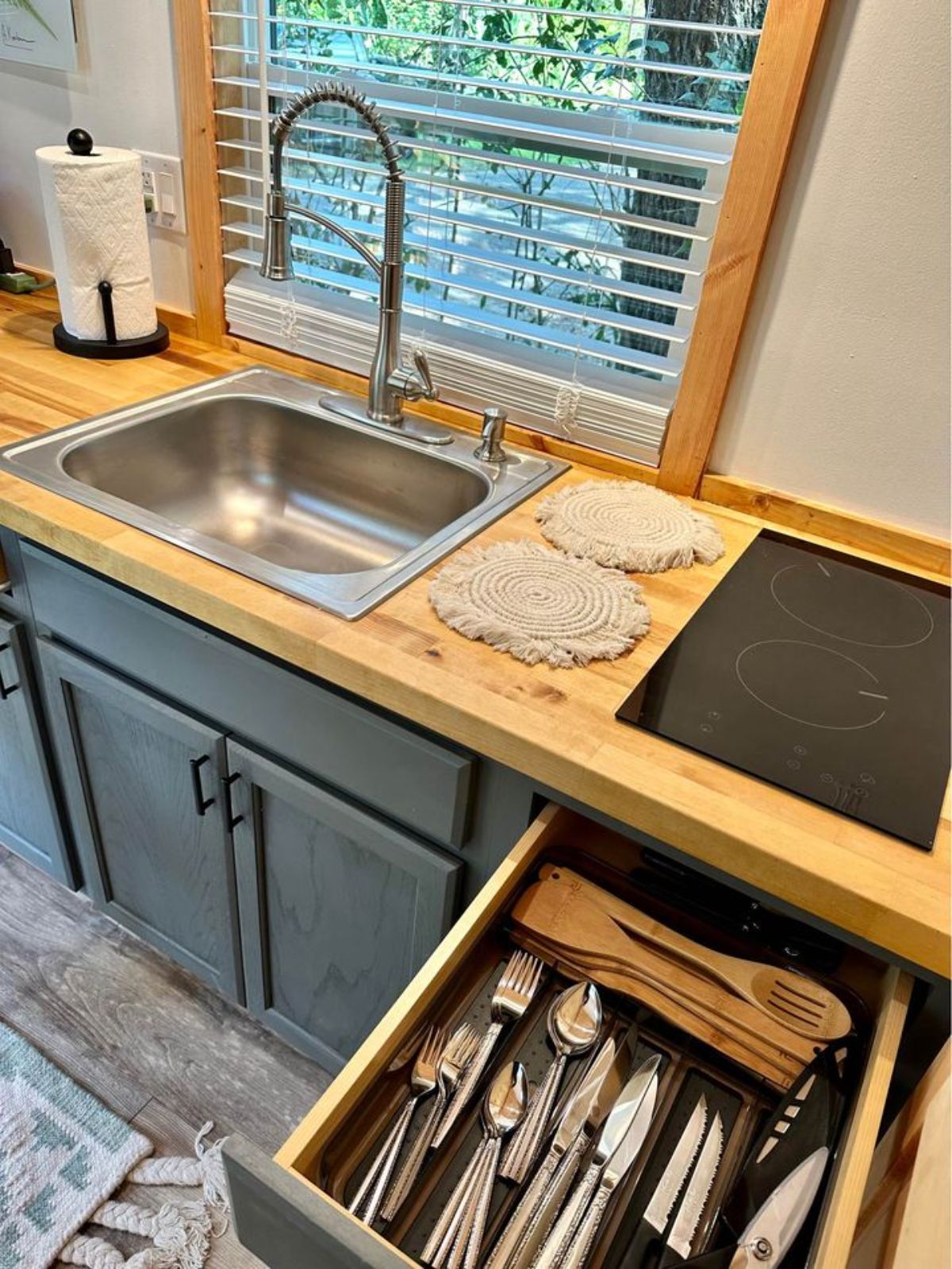 Stainless steel sink, stove and storage cabinets in the kitchen area of 20’ turnkey ready tiny house