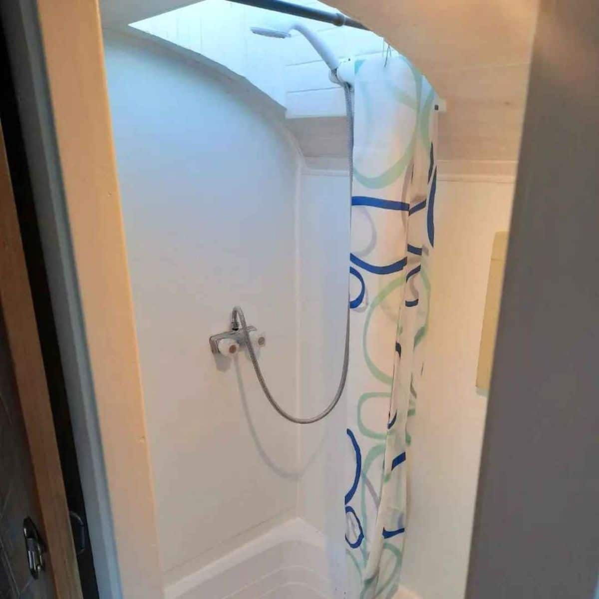 Shower area with bathtub in bathroom of converted tiny home