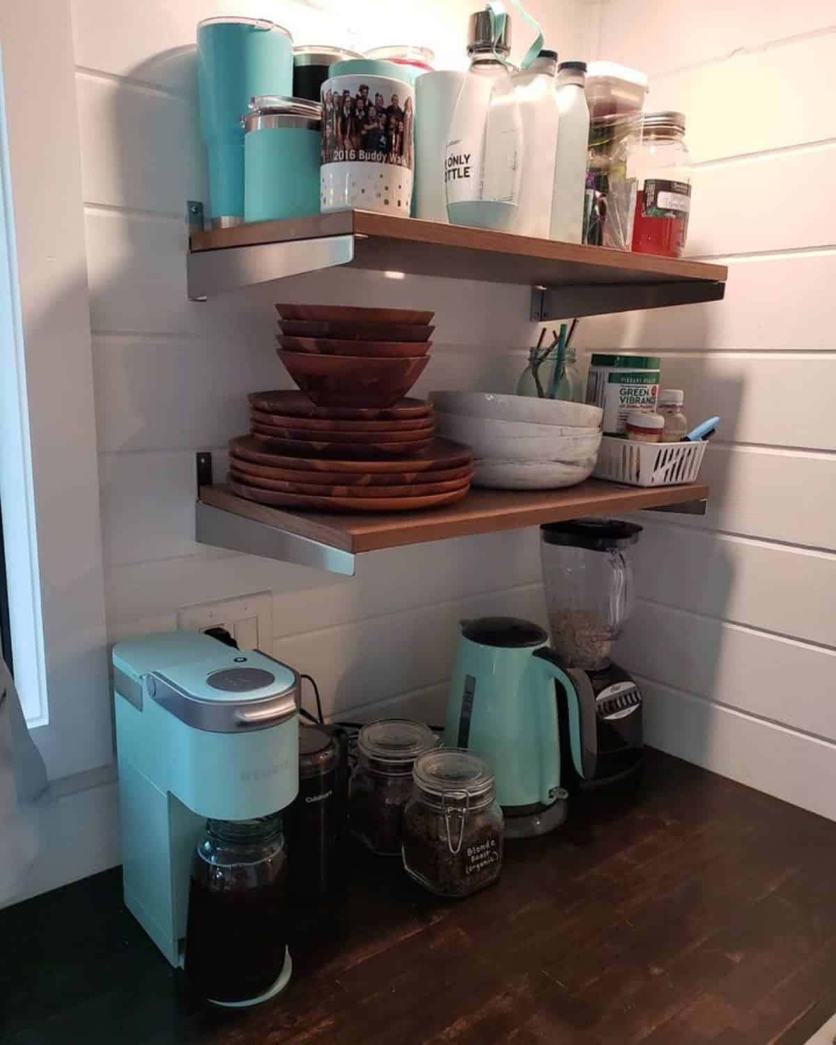 teal coffee maker and kettle on counter in kitchen with butcherblock counters and shelves against white shiplap wall