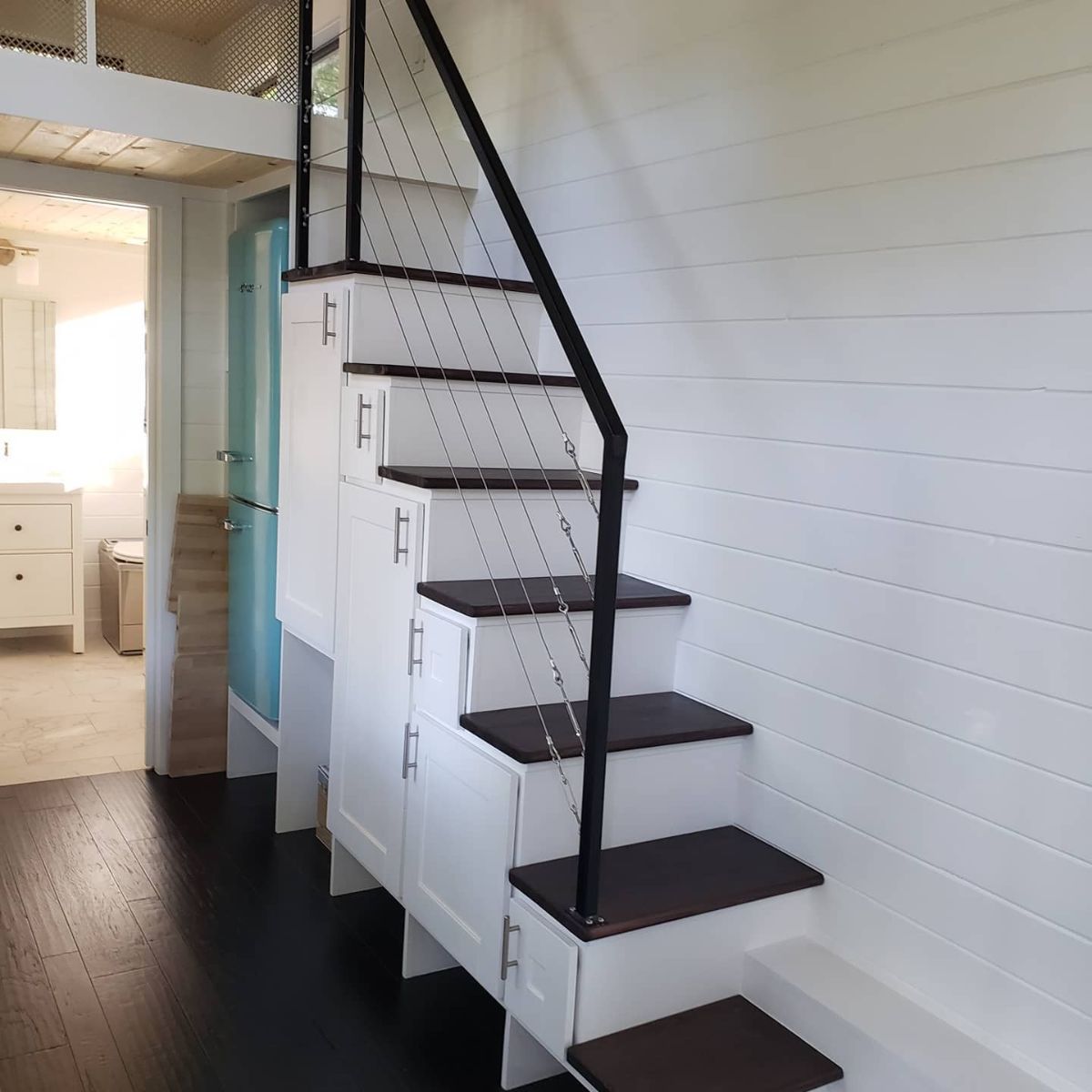 white stairs with wood tops against white shiplap wall inside tiny home