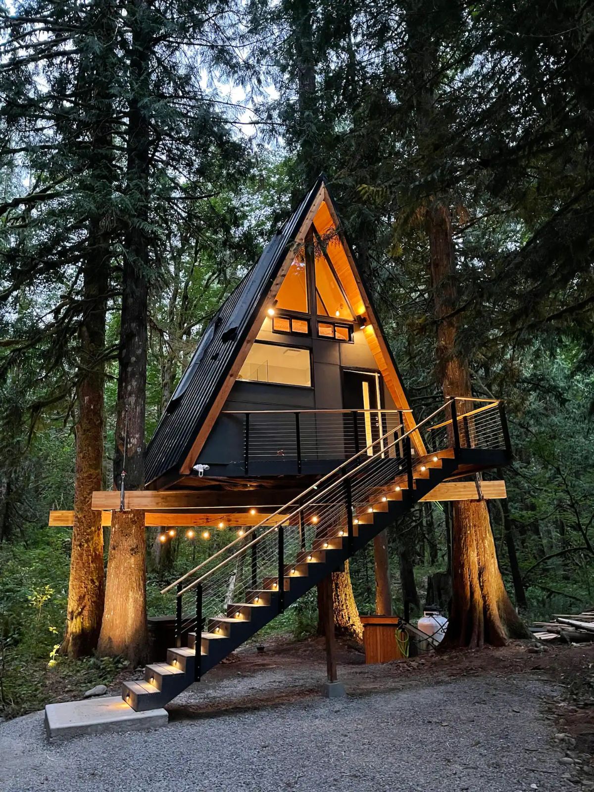 a-frame treehouse after dark with lights inside