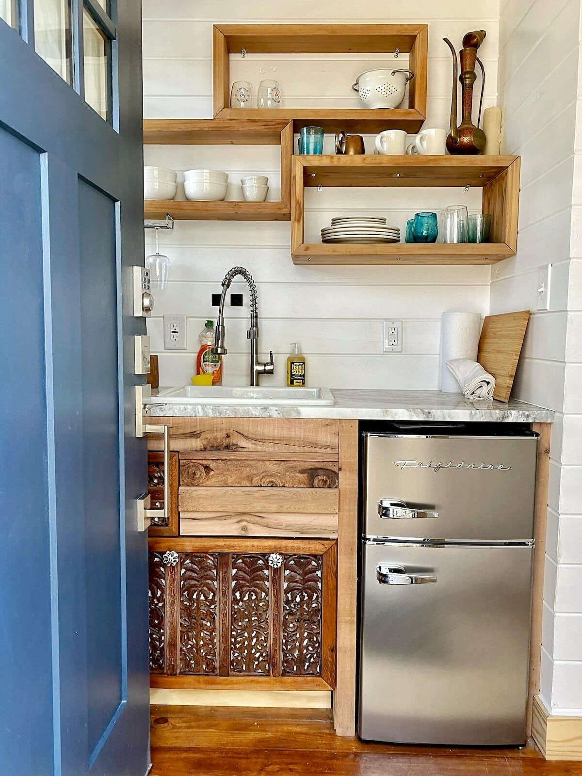 A secured entry door leads into a kitchen with a mini modern retro style Frigidaire top-freezer refrigerator with pull handles