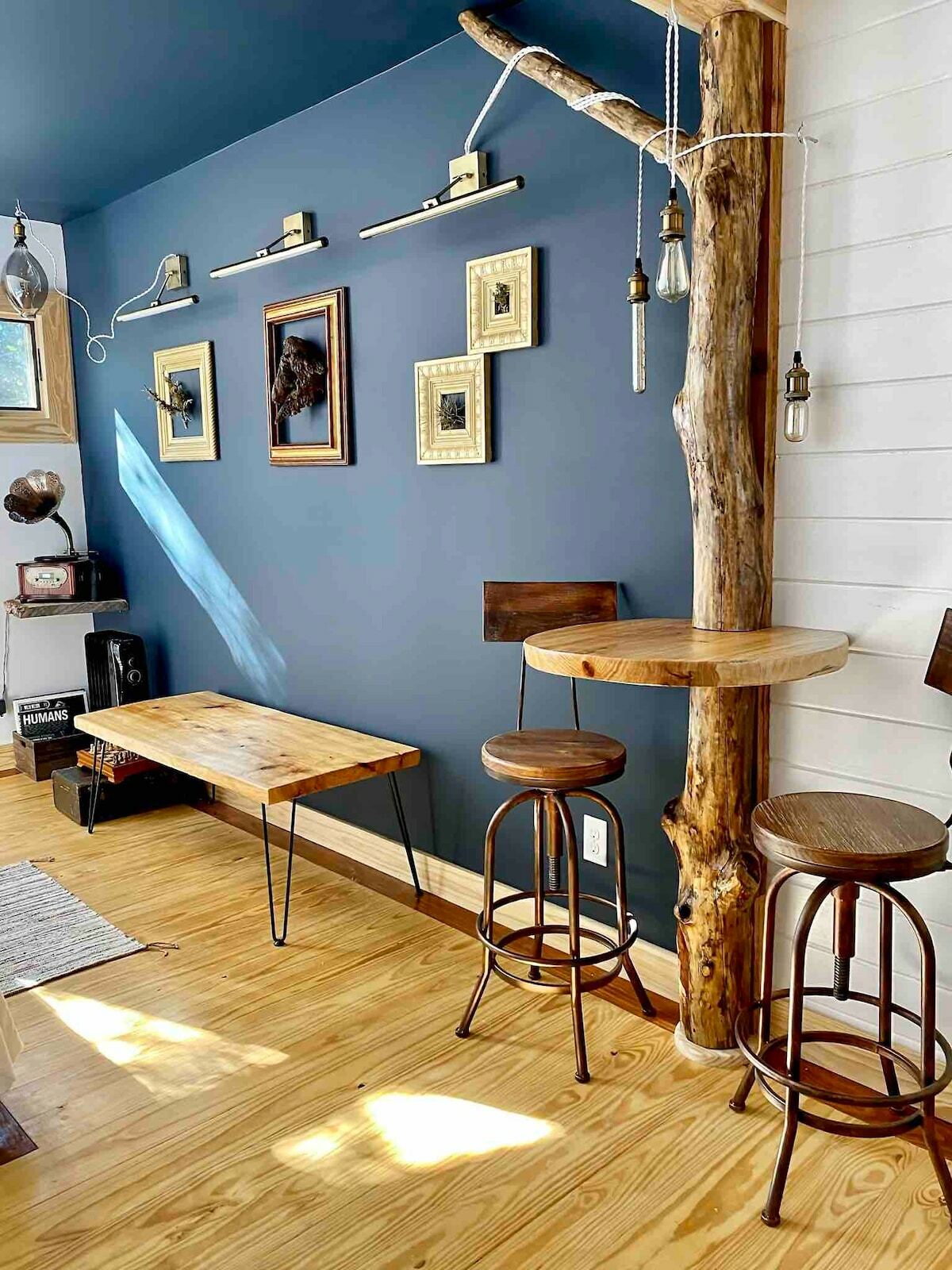 A living area with a debarked tree trunk post with an integrated natural wood slab small bar-style mini tabletop