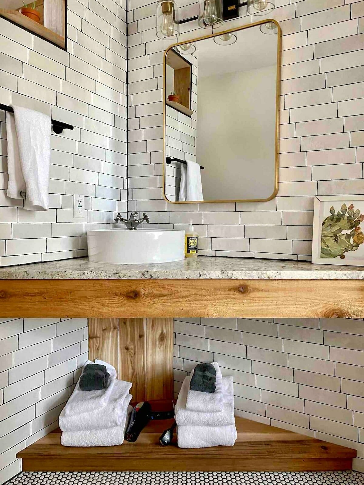 A bathroom corner vanity with a small white honeycomb tile on the floor of the main bathroom space