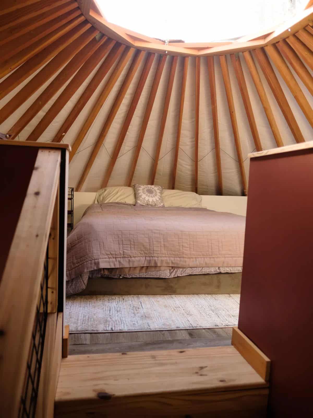 steps to bed just below opening in center of yurt