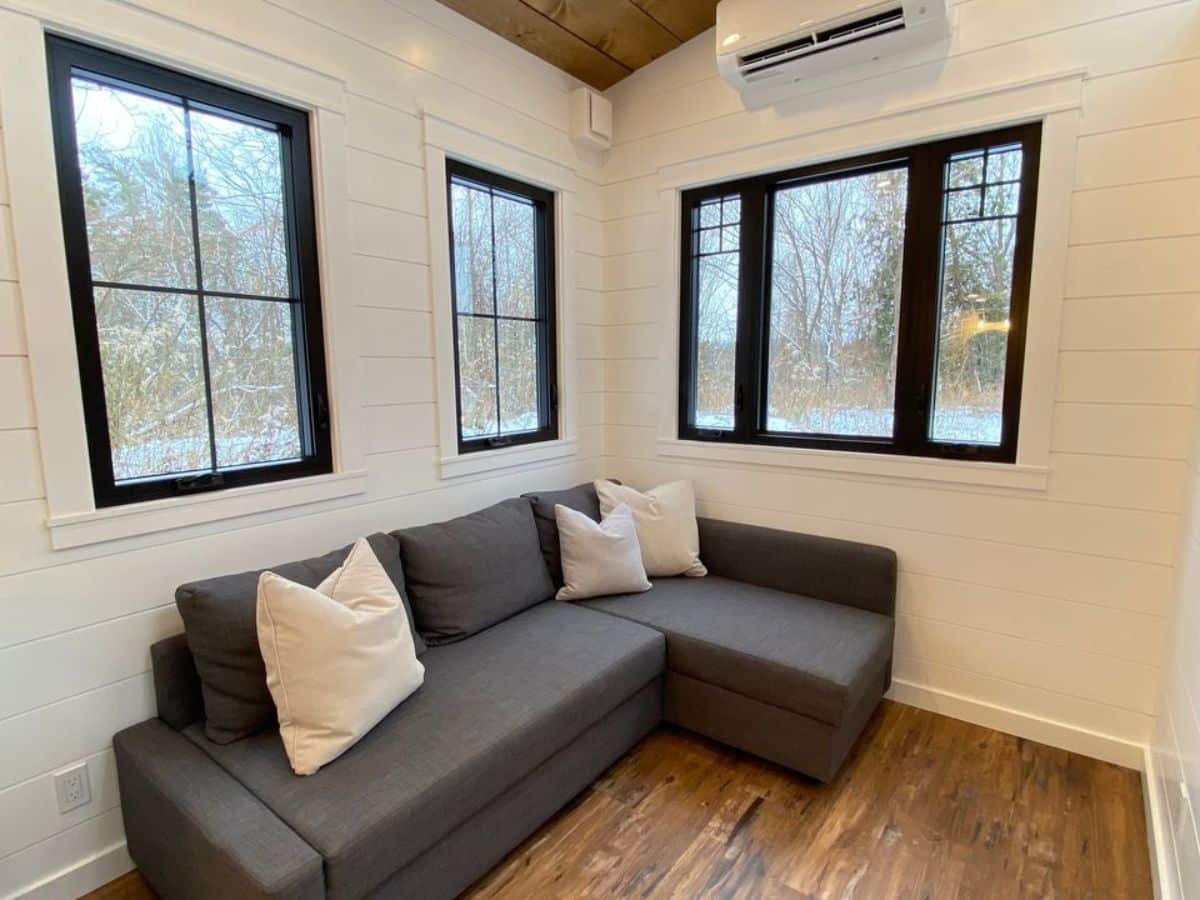 Living area of new luxurious tiny home has a couch and air condition unit
