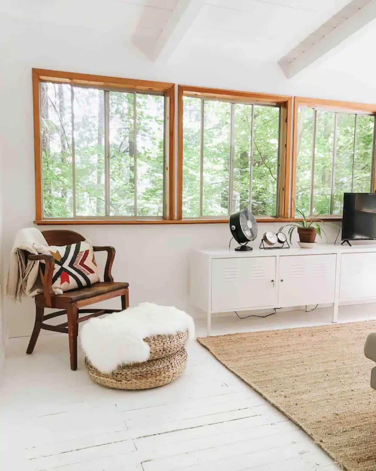 The cabin's living area, with cozy and rustic decor, featuring lots of windows that allow for an airy and bright atmosphere