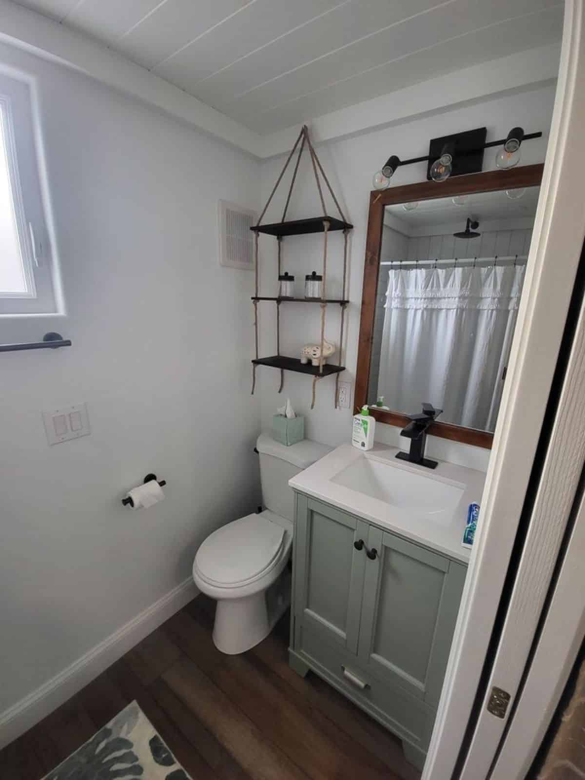 Standard toilet, sink with vanity & mirror in bathroom