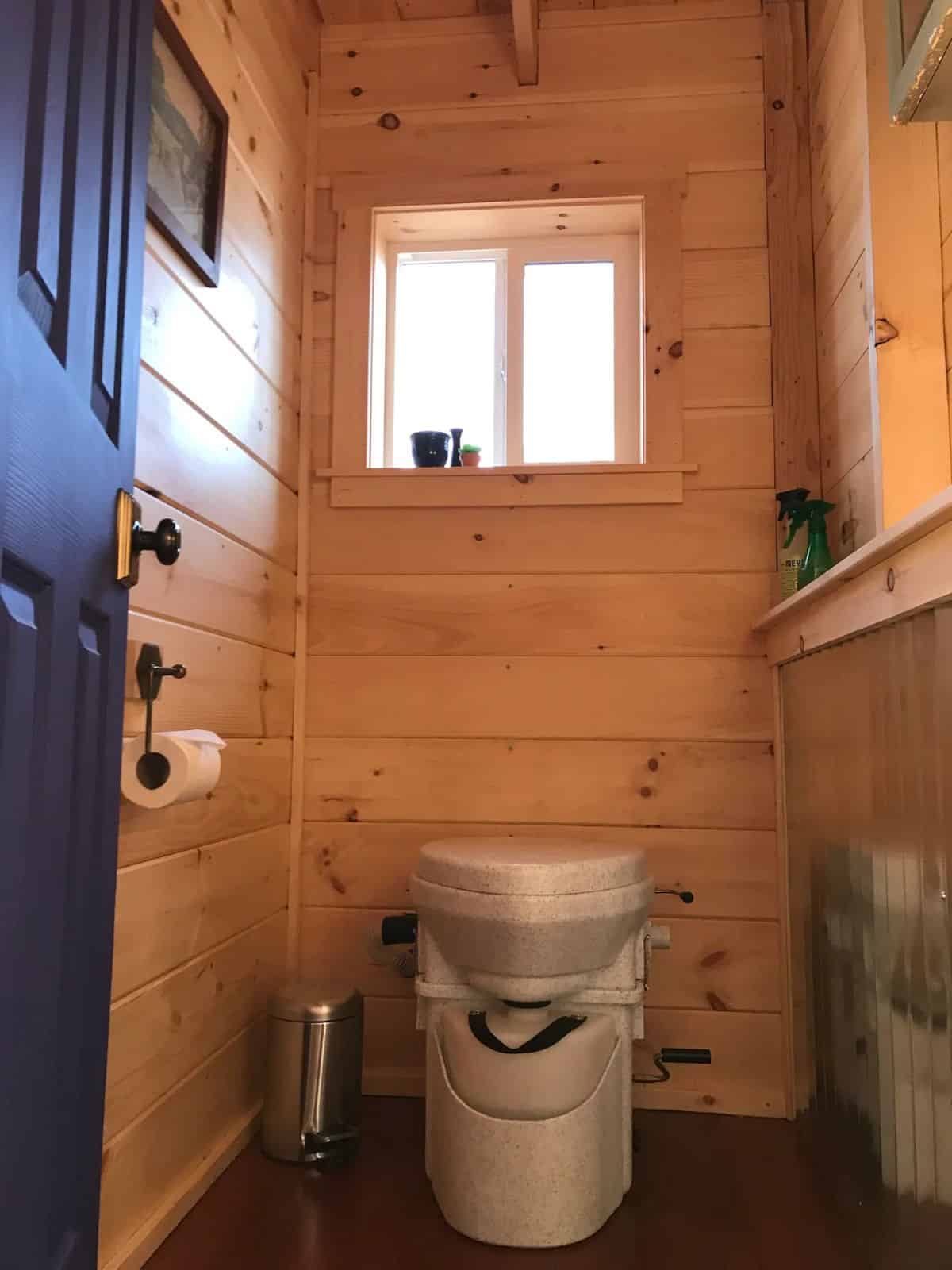 gray compost toilet in bathroom with black door